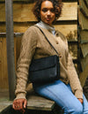 Black Leather womens handbag. Square shape with an adjustable strap. Lifestyle product image.