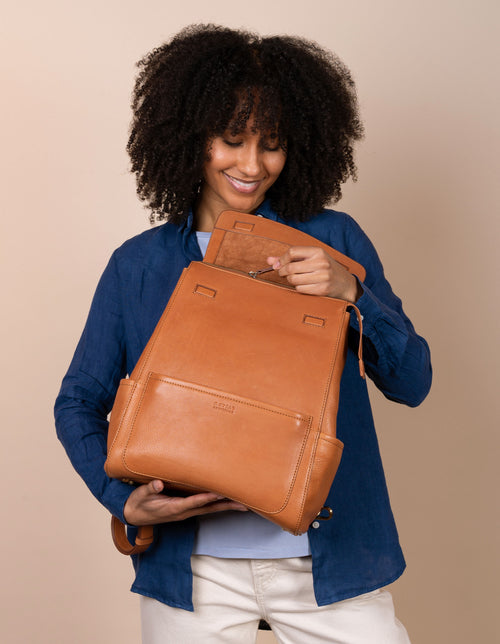 Jean Backpack in Wild Oak Soft Grain. Leather - Female model image - unzipping the bag