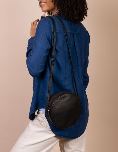 Luna Bag Black Soft Grain Leather. Circular crossbody bag for women. female model image