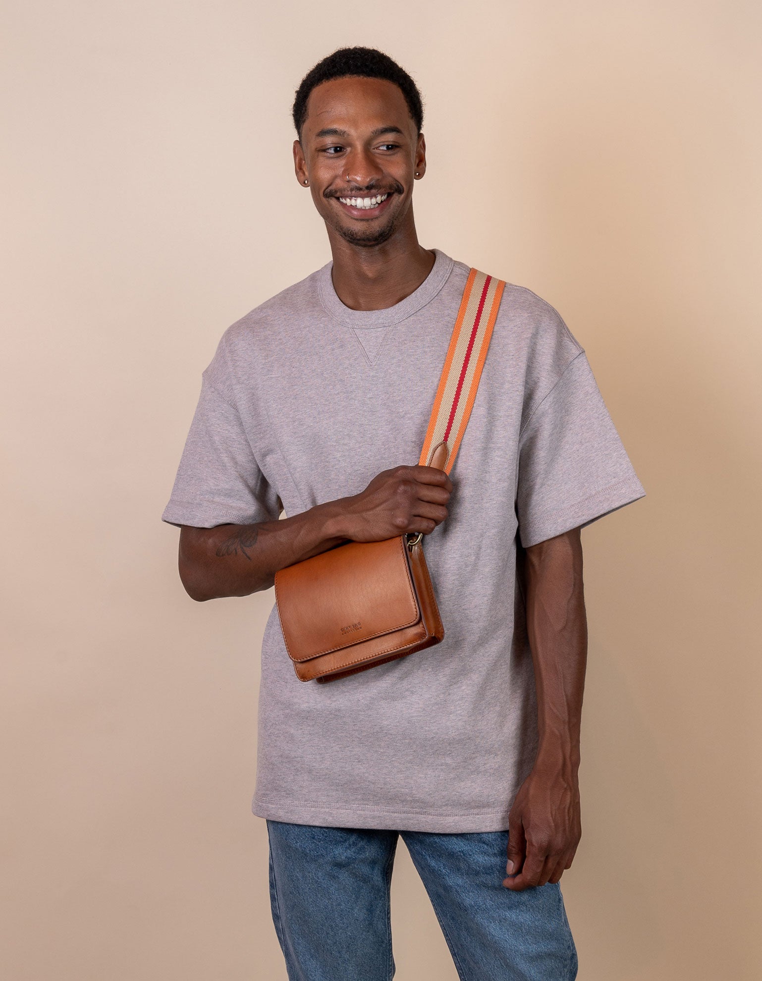 Orange & red adjustable webbing strap with cognac leather details. Male model product image.