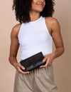 Pau Pouch Black Leather purse. Rectangular shaped fold over wallet. Female model image