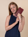 Sonny wallet in ruby classic leather. Female model product image.