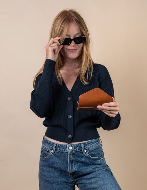 Sunglasses case in cognac classic leather. Female model product image.