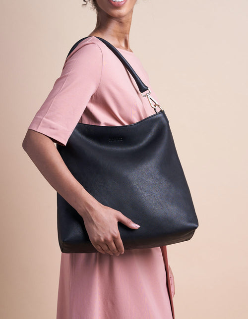 Black Leather shopper bag. Square shape with an adjustable and removable strap. Model product image.