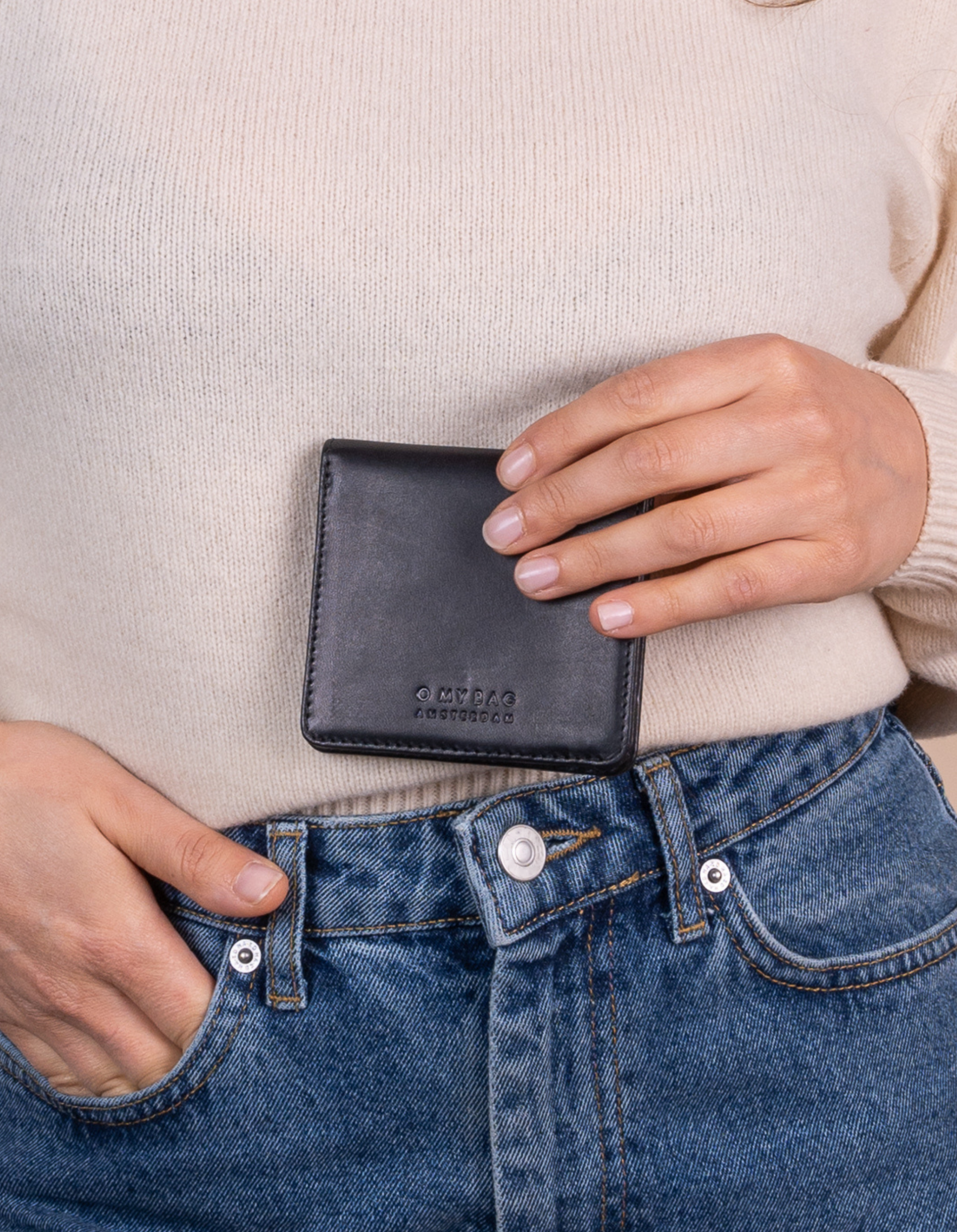 Alex fold over wallet in black classic leather. Model product image.