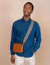 Audrey Mini Cognac leather bag. Square shape with an adjustable webbing strap. Male Model image