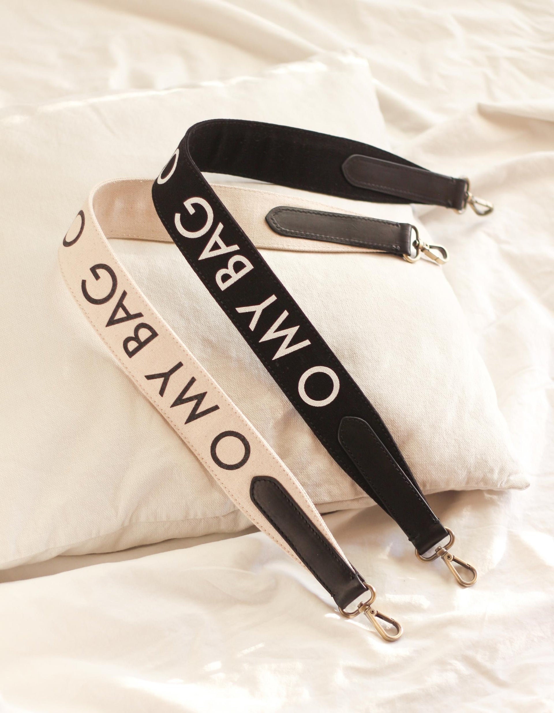 White canvas cotton handbag strap with black leather details and logo print. lifestyle image.