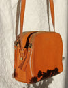 Cognac Leather womens handbag. Square shape with an adjustable strap. Lifestyle image.