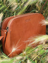 Cognac Leather womens handbag. Square shape with an adjustable strap. Lifestyle image.