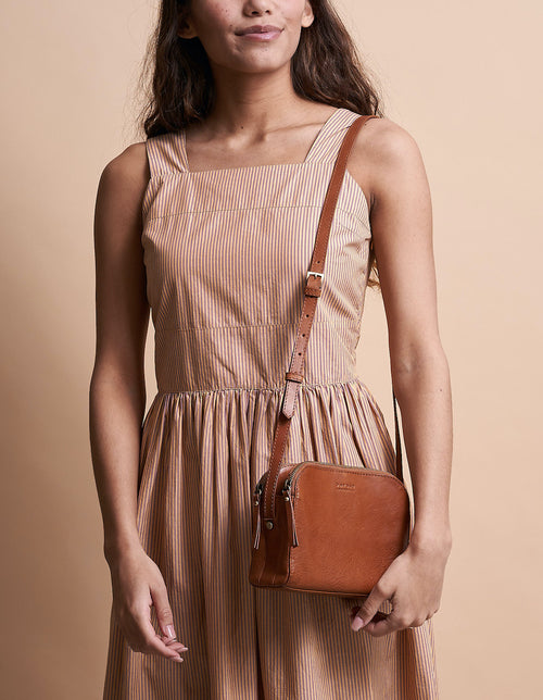 Cognac Leather womens handbag. Square shape with an adjustable strap. Model image.