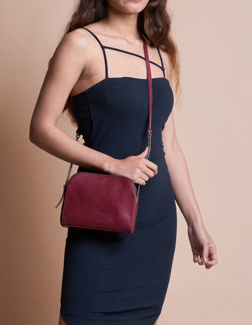 Ruby Leather womens handbag. Square shape with an adjustable leather & chain strap. Model image.
