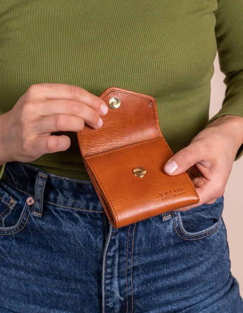 Model holding Georgie's wallet in cognac leather. Detail shot.