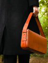 Cognac Longuette Leather womens handbag. Square shape with an adjustable strap. Model image