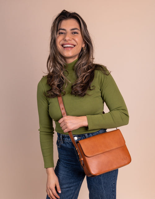 Cognac Leather womens handbag. Square shape with an adjustable strap. Lifestyle product image.