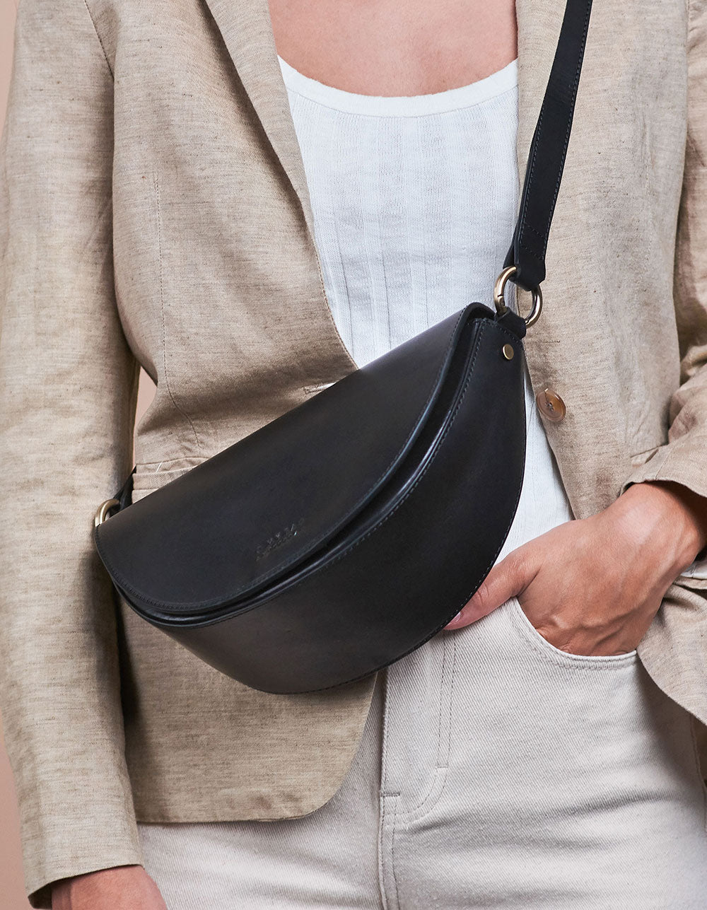 Laura Bag Black Classic Leather. Round mood shape crossbody bag for women. Model image.