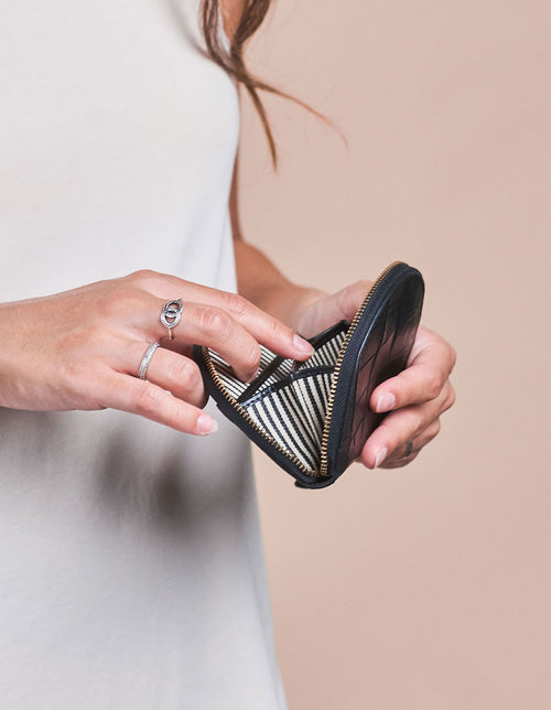 Laura Purse Black Classic Croco Leather. Round mood shape coin purse unisex wallet. Model image.